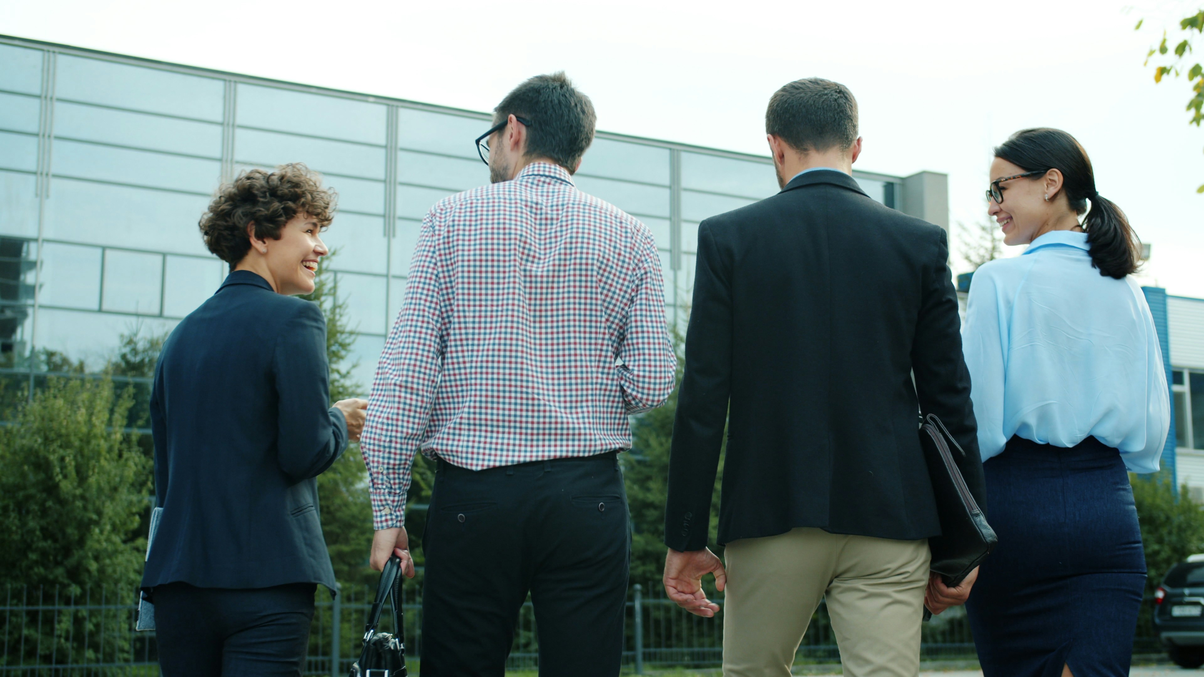 A group of four professionals walking outside, smiling and engaged in a collective discussion